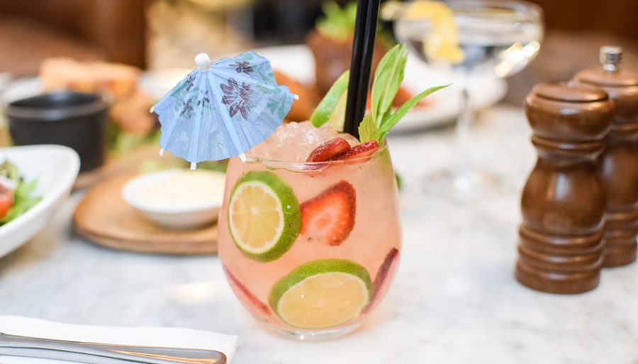 A cocktail garnished with cucumber and strawberry