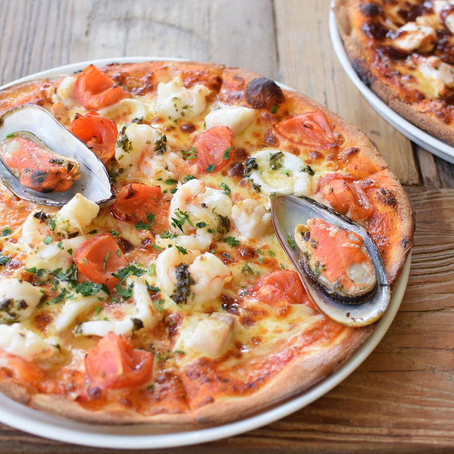 Seafood pizza topped with mussels, prawns and tomato